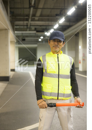 A man guiding passengers in an underground parking lot 132280085