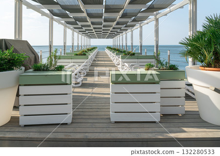 Relaxing Beachside Lounge Area With Plants and Sun Chairs on Wooden Deck Relaxing Beachside Lounge Area With Plants and Sun Chairs on Wooden Deck 132280533