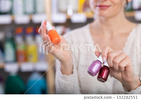 Close-view of hands of female buyer holding colorful nail polish Close-view of hands of female buyer holding colorful nail polish 132282551