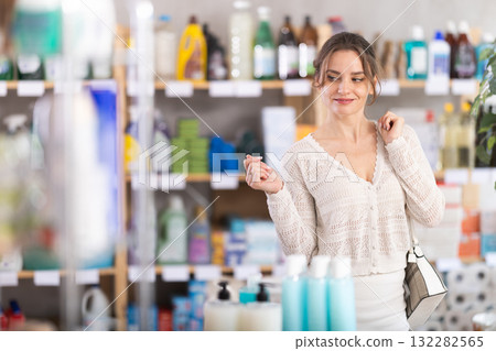 Woman wanders around store, looking at display cases Woman wanders around store, looking at display cases 132282565