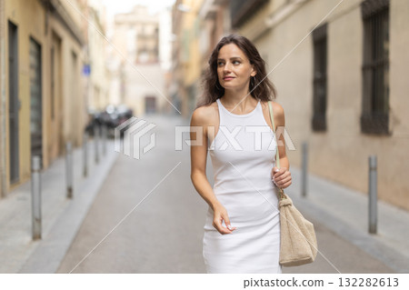 Young woman walks along city street 132282613