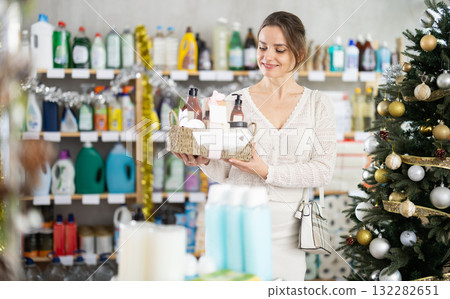 In household chemicals store, woman examines composition of shower cosmetic kit, X Mas gift set In household chemicals store, woman examines composition of shower cosmetic kit, X Mas gift set 132282651