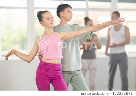 Teenage girl practicing ballet positions in pair with boy in dance studio 132282671