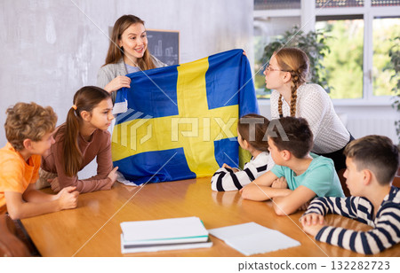 Teacher showing Sweden flag to group of schoolchildren Teacher showing Sweden flag to group of schoolchildren 132282723