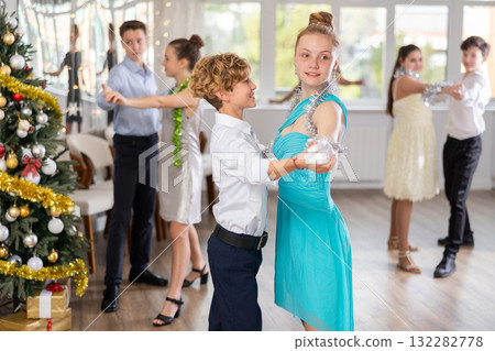 Teen boy and girl dancing waltz in couple during lesson at studio in New Year atmosphere 132282778