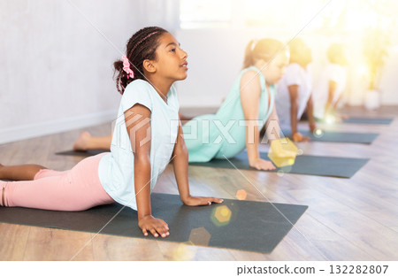 In studio with group of friends African girl stand perform dog muzzle up, Urdhva Mukha Shvanasana In studio with group of friends African girl stand perform dog muzzle up, Urdhva Mukha Shvanasana 132282807