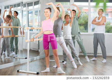 Teacher conducts class with teen girls and boys in ballet studio, observes doing Batman exercise. Teacher conducts class with teen girls and boys in ballet studio, observes doing Batman exercise. 132282859