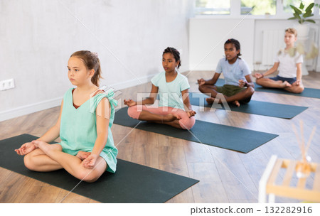 Training yoga kids on yoga mat in gym. 132282916