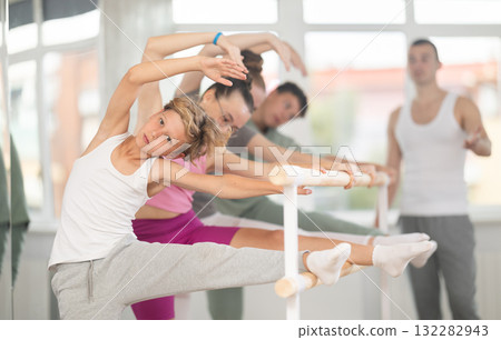 Ballet pose grand batman - girls and boys at a choreography lesson are learning ballet movements in studio Ballet pose grand batman - girls and boys at a choreography lesson are learning ballet movements in studio 132282943
