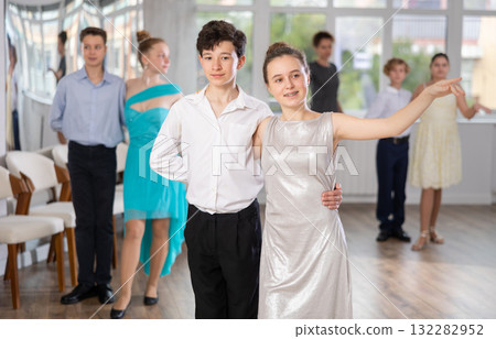 Positive teen boy and girl are dancing classic version of waltz in couple during lesson at studio 132282952