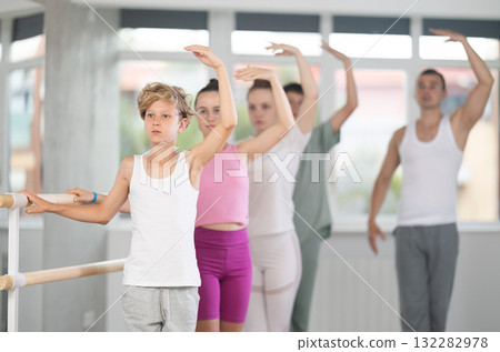 Girls and boys in ballet class perform third position under male teacher guidance. 132282978