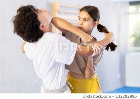 Group of children in sportswear exercising self protection techniques in pair during class at gym Group of children in sportswear exercising self protection techniques in pair during class at gym 132282980