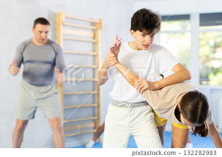 Preteen children pairs learning strength self-defense in gym Preteen children pairs learning strength self-defense in gym 132282983