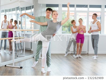 Teenage girl and boy practicing arabesque position of ballet in dance studio 132282989