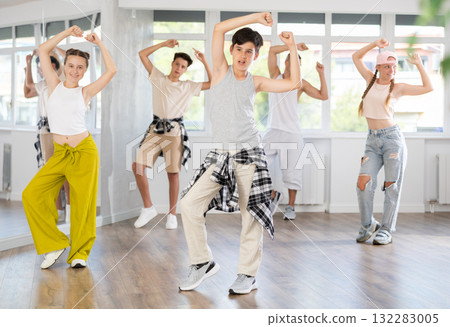 Teen guy together with group of teenage friends, learn to dance hip hop in choreographic hall. 132283005