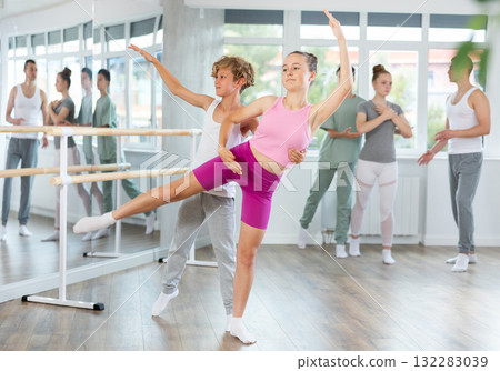 Teenage girl and boy practicing arabesque position of ballet in dance studio Teenage girl and boy practicing arabesque position of ballet in dance studio 132283039