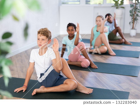 Preteen children exercising yoga in pose Gomukhasana in fitness center Preteen children exercising yoga in pose Gomukhasana in fitness center 132283040