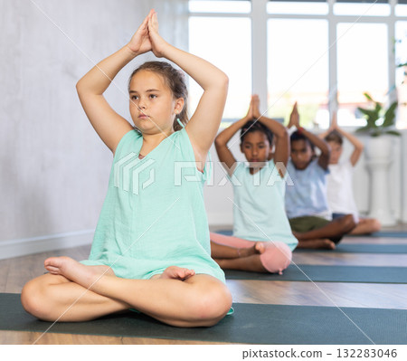 Children together making yoga meditation in lotus pose in fitness studio Children together making yoga meditation in lotus pose in fitness studio 132283046