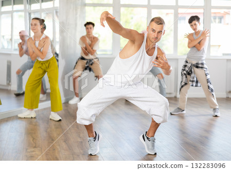 Young guy dancing hip-hop against background of group members Young guy dancing hip-hop against background of group members 132283096