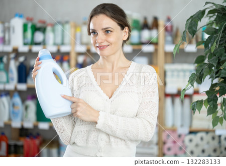 Young woman buyer chooses detergent in store Young woman buyer chooses detergent in store 132283133