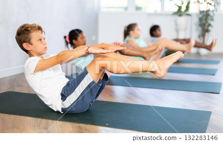 School kids training yoga on yoga mat in gym. 132283146