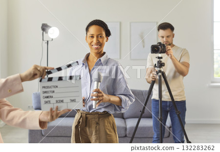 Filming interview or media content in studio, smiling woman holding microphone looking at camera 132283262