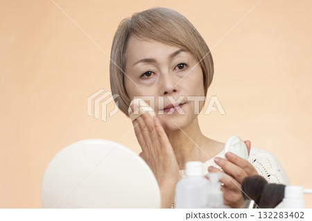 Senior woman putting on makeup Senior woman putting on makeup 132283402