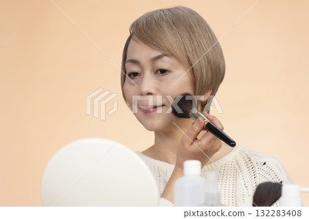 Senior woman putting on makeup Senior woman putting on makeup 132283408