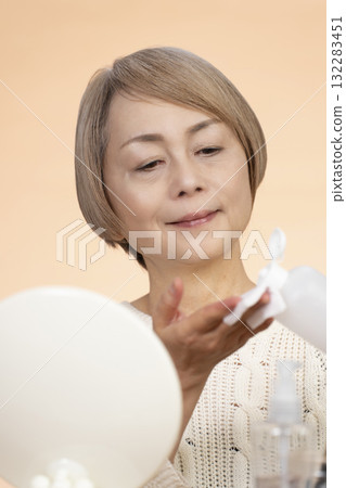Senior woman putting on makeup Senior woman putting on makeup 132283451