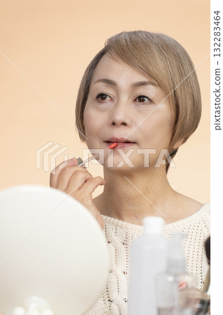 Senior woman putting on makeup Senior woman putting on makeup 132283464