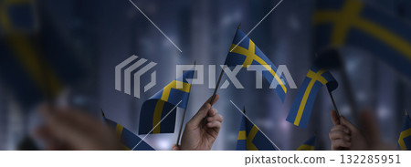 Sweden flags in their hands on a blurred urban background 132285951