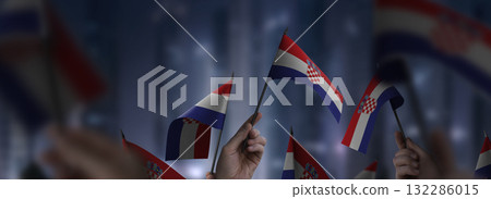 Croatia flags in their hands on a blurred urban background Croatia flags in their hands on a blurred urban background 132286015