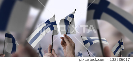 Finland flags in their hands on a blurred urban background 132286017