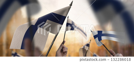 Finland flags in their hands on a blurred urban background 132286018