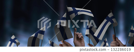 Finland flags in their hands on a blurred urban background 132286019