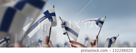 Finland flags in their hands on a blurred urban background Finland flags in their hands on a blurred urban background 132286020