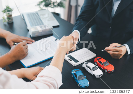 Business handshake after signing car loan contract, symbol of trust and successful auto finance agreement with money, calculator and vehicle model on desk, concept of deal and partnership. car loan. Business handshake after signing car loan contract, symbol of trust and successful auto finance agreement with money, calculator and vehicle model on desk, concept of deal and partnership. car loan. 132286277