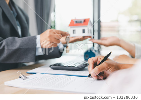 Close up of business people signing loan agreement contract with pen and paperwork on desk, financial deal concept with laptop and calculator in modern office environment. loan agreement contract. Close up of business people signing loan agreement contract with pen and paperwork on desk, financial deal concept with laptop and calculator in modern office environment. loan agreement contract. 132286336