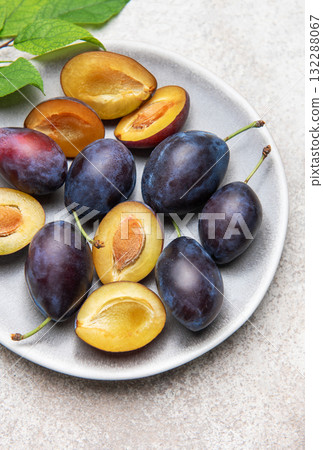Fresh plums on plate showing halved fruit composition Fresh plums on plate showing halved fruit composition 132288067