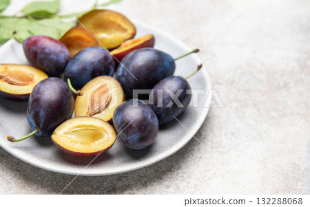 Fresh plums on plate showing halved fruit composition Fresh plums on plate showing halved fruit composition 132288068