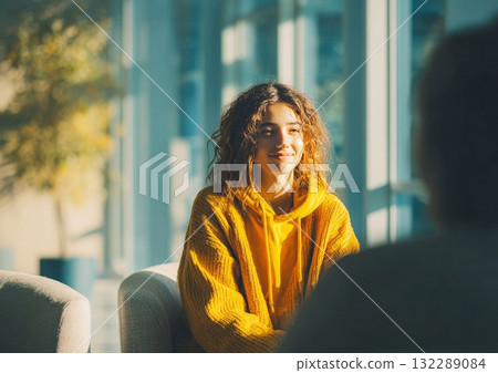 Young woman smiling, listening during conversation in office 132289084