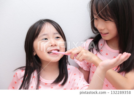 Two sisters, ages 4 and 10, brushing their teeth in pajamas Two sisters, ages 4 and 10, brushing their teeth in pajamas 132289358