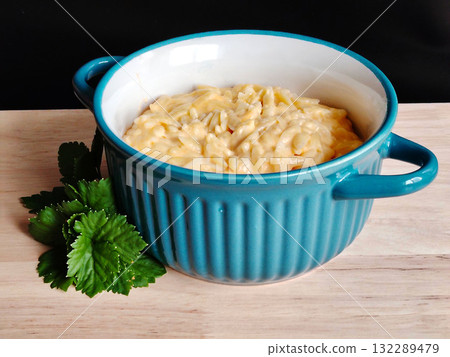 Creamy macaroni and cheese in blue ceramic bowl on wooden table. 132289479