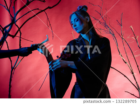 Woman poses in traditional Japanese dress with striking background and branches 132289705