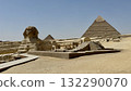 A landscape of ancient statues and pyramids under the blue sky - Desert landscape of adventure and tourism 132290070