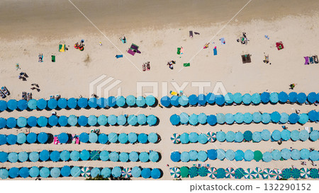Blue umbrellas with tourists relaxing at Kata beach in Phuket, Thailand. Blue umbrellas with tourists relaxing at Kata beach in Phuket, Thailand. 132290152