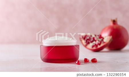Red glass cream jar with white lid slightly open, showcasing pomegranate oil skincare, promoting healthy lifestyle and botanical cosmetic ingredients 132290354