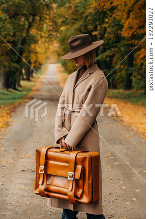 European woman in coat and hat walks along yellow autumn trees European woman in coat and hat walks along yellow autumn trees 132291022