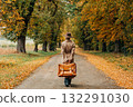 European woman in coat and hat walks along  yellow autumn trees 132291030
