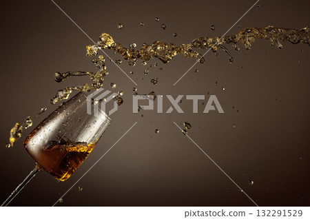 Glass and white wine splash on a beige background. Glass and white wine splash on a beige background. 132291529
